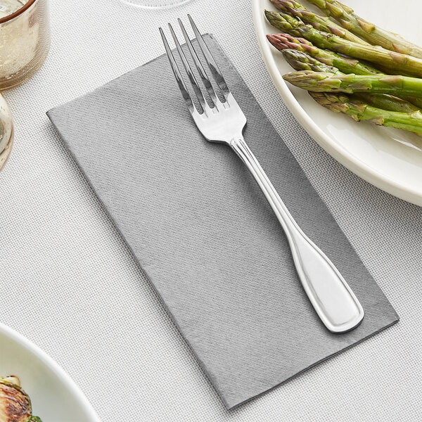A fork on a Hoffmaster FashnPoint Slate Dinner Napkin next to a plate of asparagus.