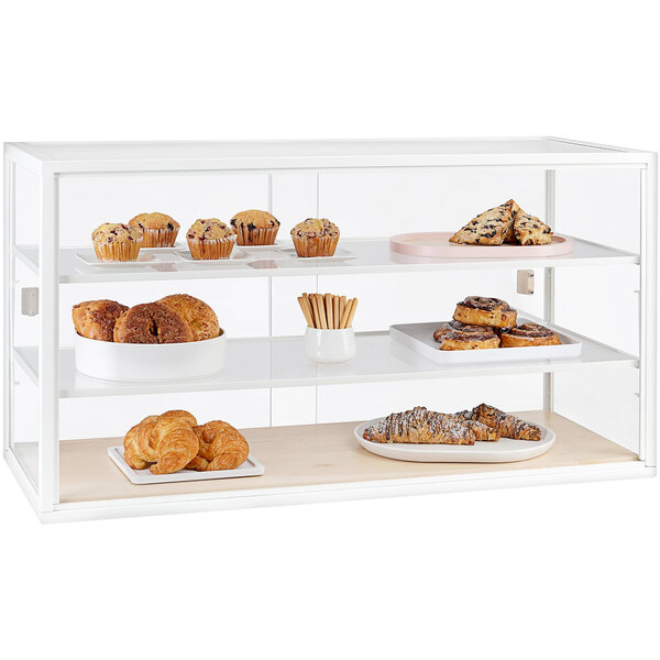 A Cal-Mil maple wood front display case with three shelves of pastries and muffins behind glass.