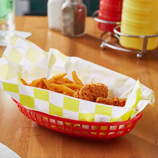 A basket of fried chicken and yellow check sandwich wrap on a table.