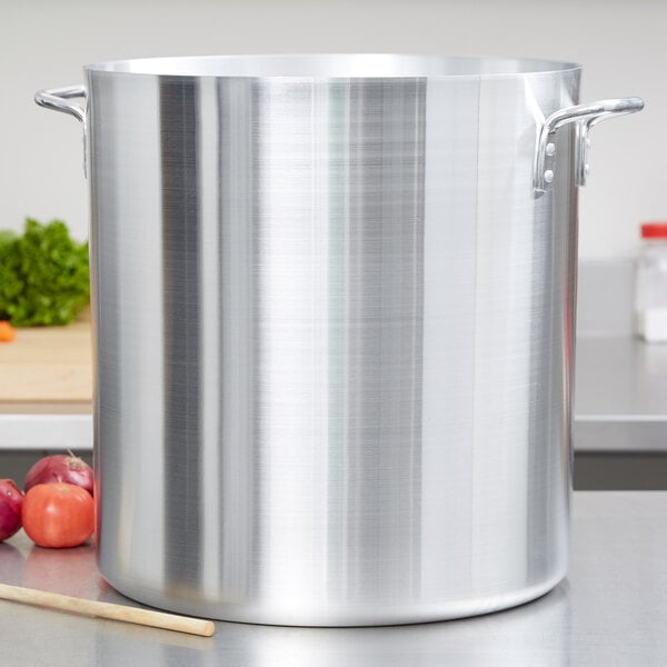A large silver Vollrath Arkadia stock pot with handles on a counter.