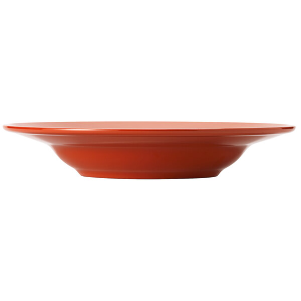 A Libbey Cantina cayenne melamine pasta bowl on a table with a red plate.