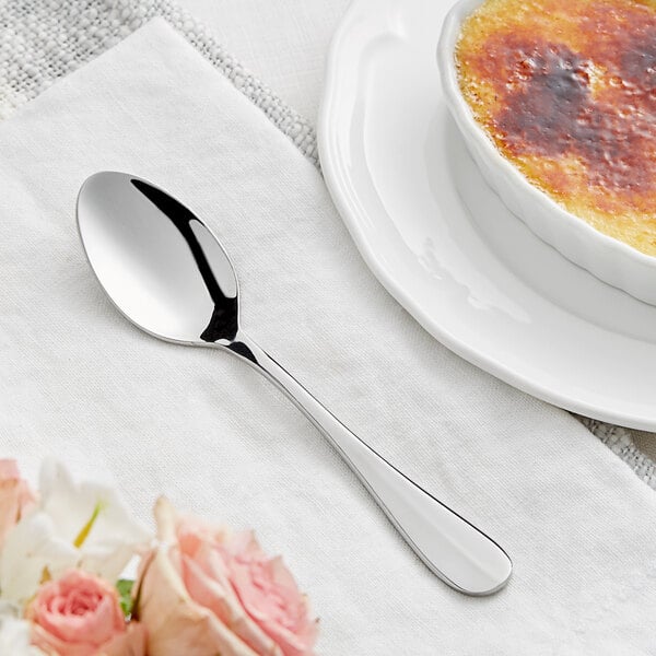 An Acopa Brigitte stainless steel teaspoon on a white plate with a brown and white creme brulee.