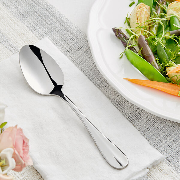 An Acopa Brigitte stainless steel serving spoon on a plate of vegetables.