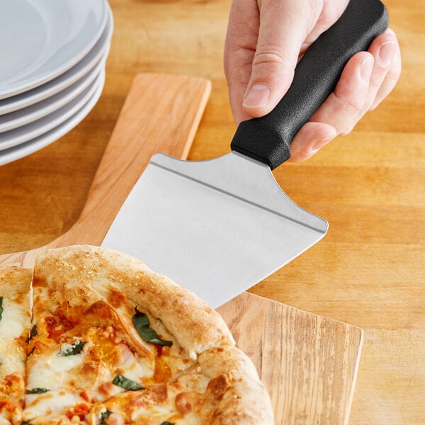 A person using an American Metalcraft pizza server with a black handle to cut a pizza.