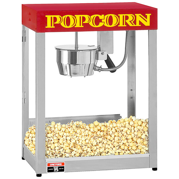 A Cretors countertop popcorn popper with popcorn inside and a red and white top.