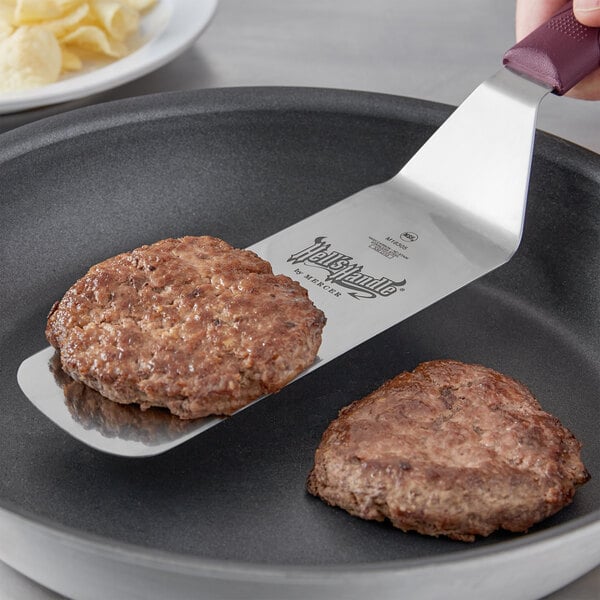 A Mercer Culinary Hell's Handle spatula cooking burgers in a pan.