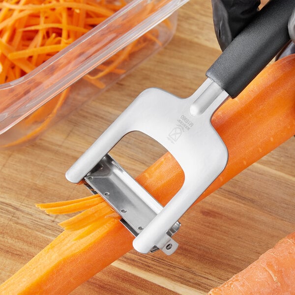 A person using a Mercer Culinary stainless steel julienne vegetable peeler to julienne carrots.
