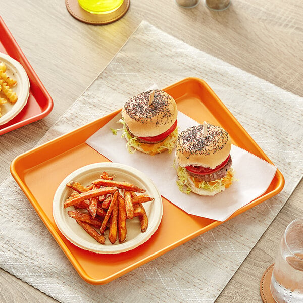 A Baker's Mark orange non-stick aluminum sheet tray with two hamburgers and fries on it.