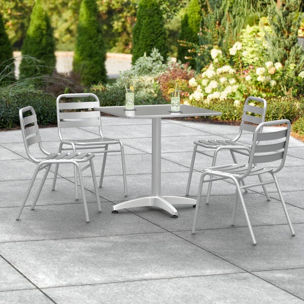 A Lancaster Table & Seating chrome square outdoor table with two white chairs.