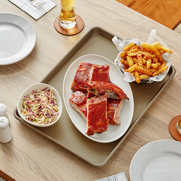 A Baker's Mark non-stick aluminum sheet tray with ribs, fries, and coleslaw on it.