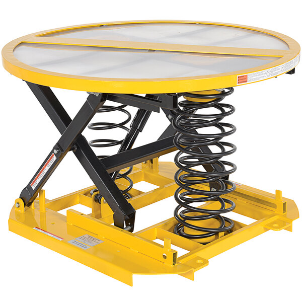 A yellow and black metal Vestil scissor lift table with springs and wheels.