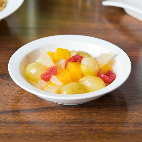 A bowl of fruit in a white Arcoroc porcelain bowl on a table.