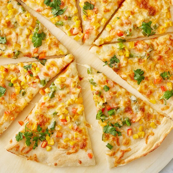 A pizza with cheese, corn, and herbs on a plate.