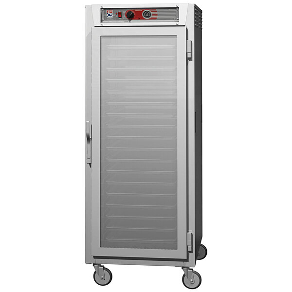 A Metro stainless steel holding cabinet with clear glass door and wheels.