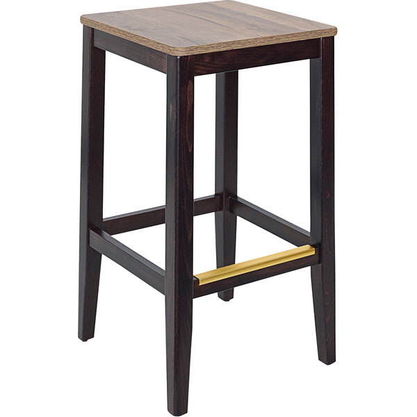 A BFM Seating Stockton dark walnut beechwood backless barstool with a wooden seat.