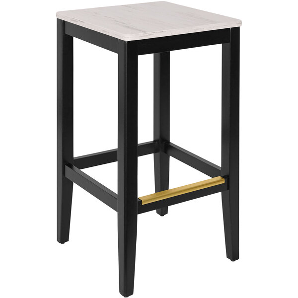 A black BFM Seating Stockton bar stool with a gold seat on a table in a bar.