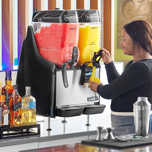 A woman using a Narvon Summit slushy machine to make a drink.