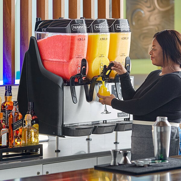 A woman pouring juice into a yellow Narvon Summit drink dispenser.
