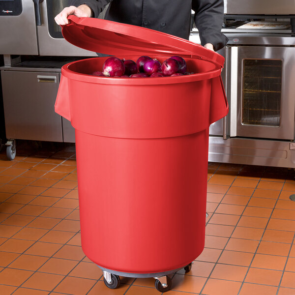 A man holding a red 55 gallon mobile ingredient storage bin full of onions.