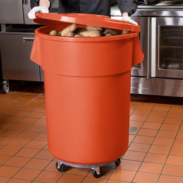 A man in a chef's uniform using an orange mobile ingredient storage bin to hold potatoes.