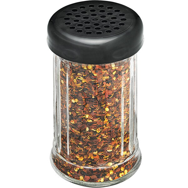 A Tablecraft clear plastic fluted shaker with a black perforated top filled with red and black pepper flakes.