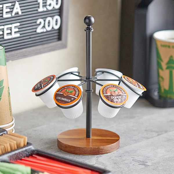 A Tablecraft black powder-coated steel and acacia wood cone and K-cup holder on a table with coffee cups.