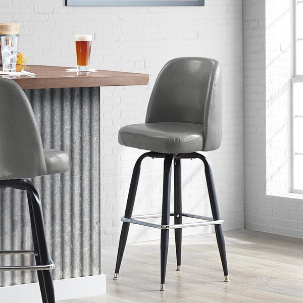A Lancaster Table & Seating Slate Gray Vinyl bar stool with black legs.