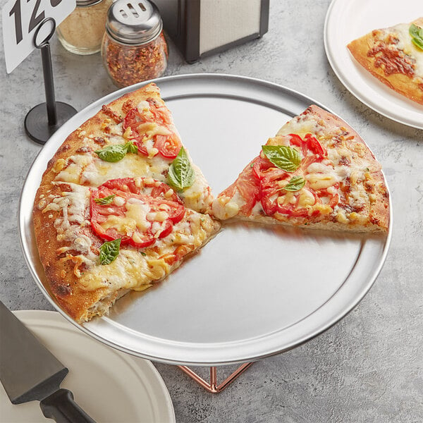 A slice of pizza with tomatoes and basil on a Choice aluminum pizza pan.