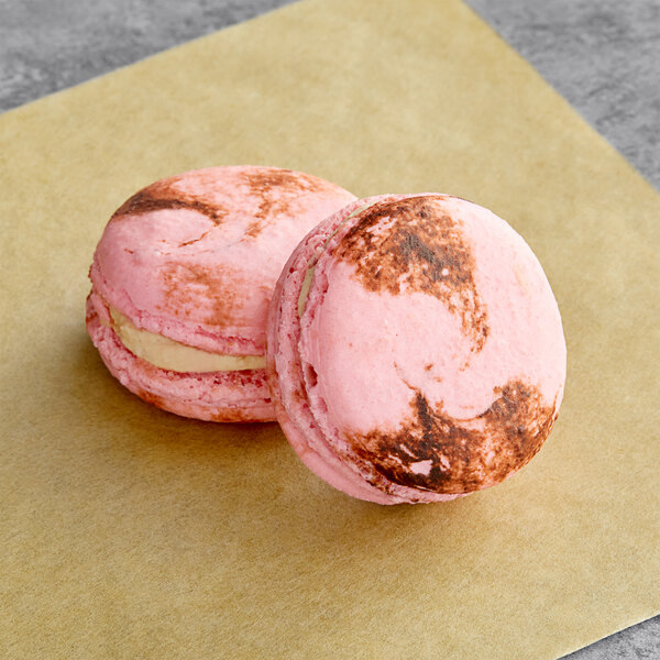 Two pink Macaron Centrale macarons with peanut butter and jelly filling.