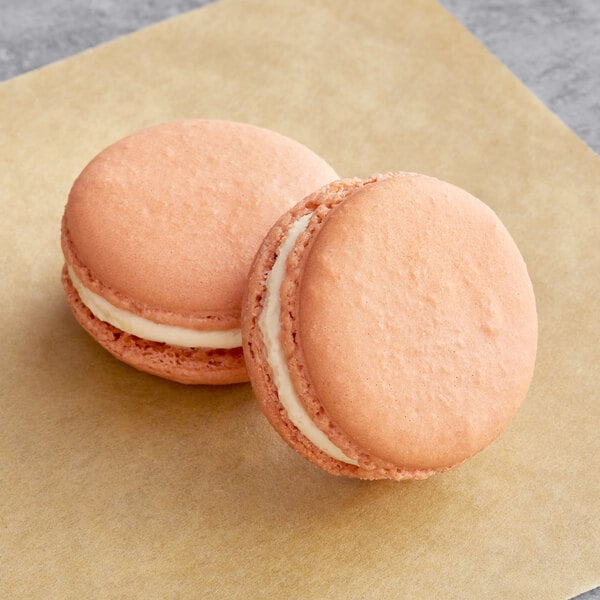 Two salted caramel Macaron Centrale macarons on a piece of paper.