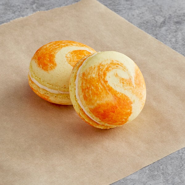 Two Peaches and Cream Macarons on a piece of paper.