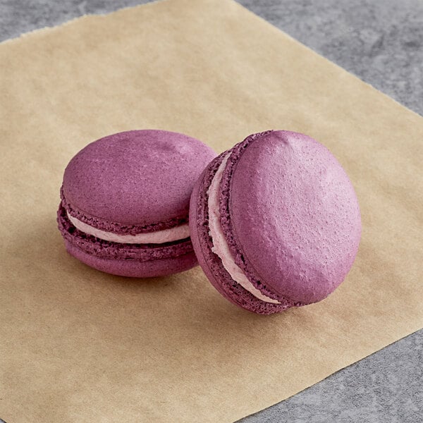 Two Ube Macarons on a brown paper.