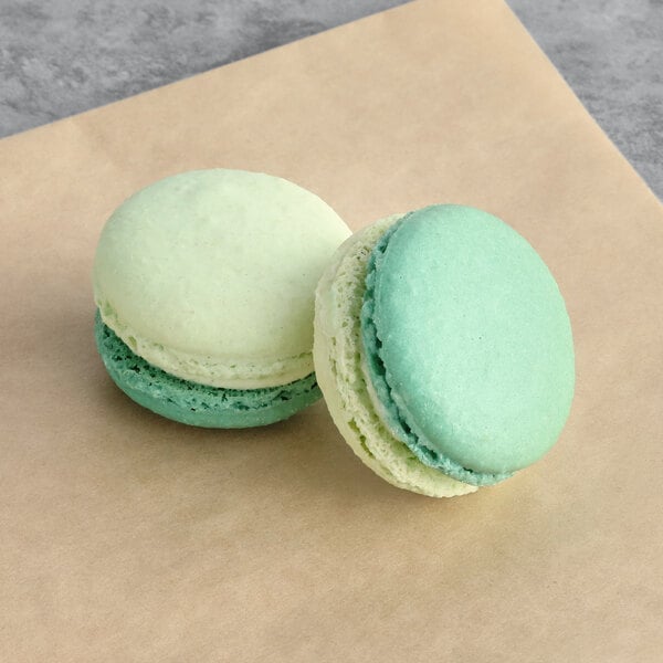 Two Macaron Centrale honeydew macarons on a brown paper.