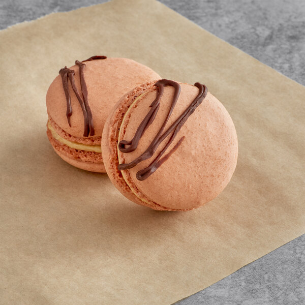 Two Macaron Centrale chocolate peanut butter macarons on a paper.
