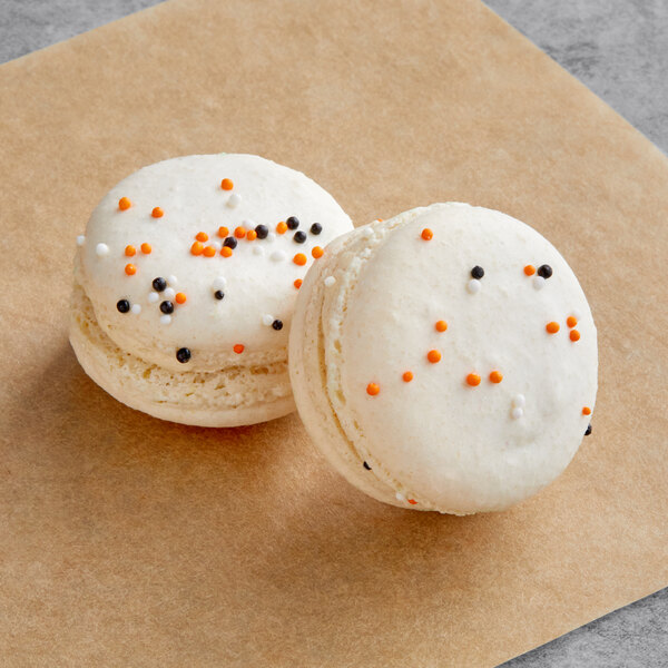 Two white Macaron Centrale macarons with sprinkles on top.