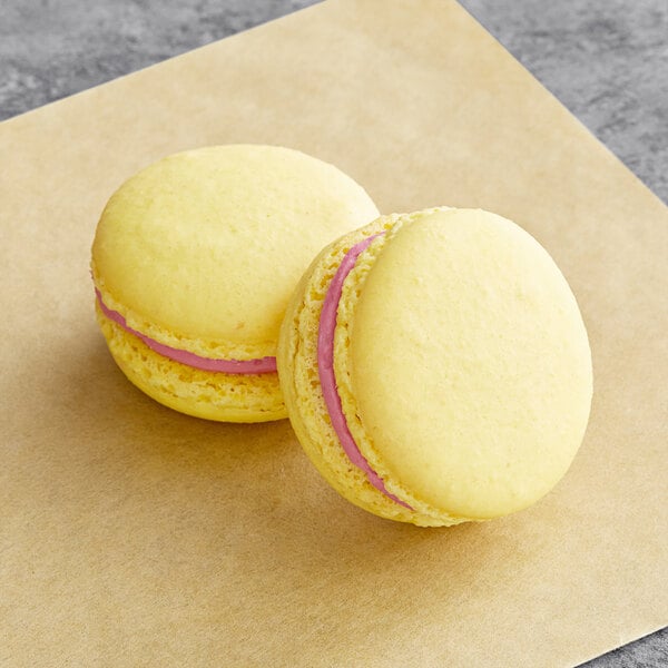 Two yellow Macaron Centrale with pink filling.