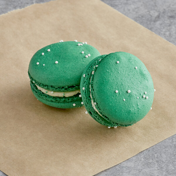 Two lime green Macaron Centrale macarons on brown paper.