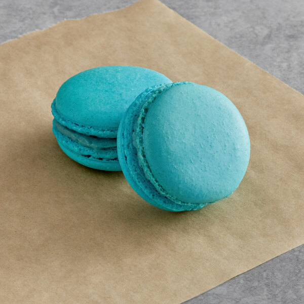 Two blue Macaron Centrale macarons on brown paper.