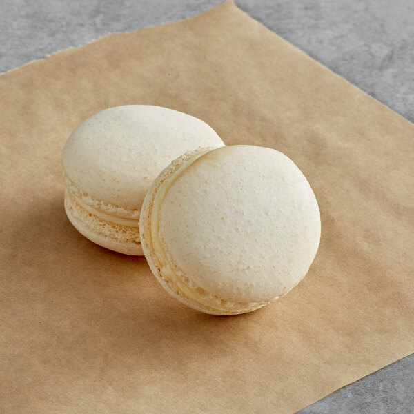 Two vanilla Macaron Centrale macarons on brown paper.
