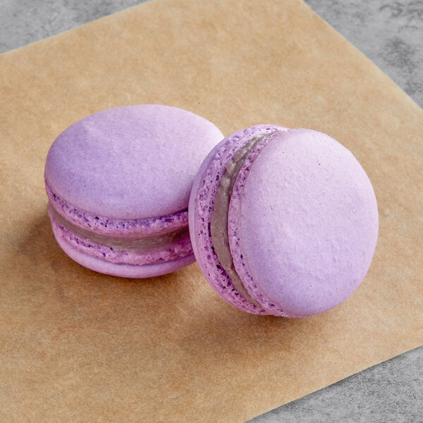 Two Macaron Centrale grape macarons on a brown surface.