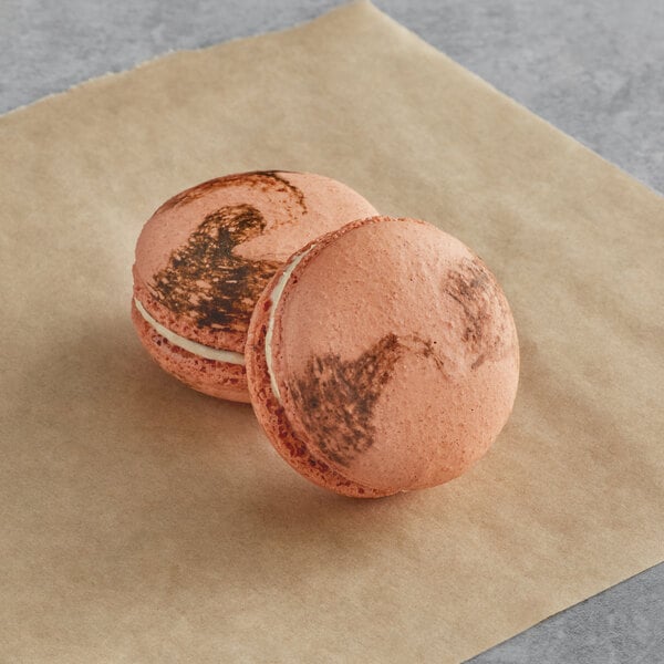 Two Macaron Centrale coffee macarons on brown paper.