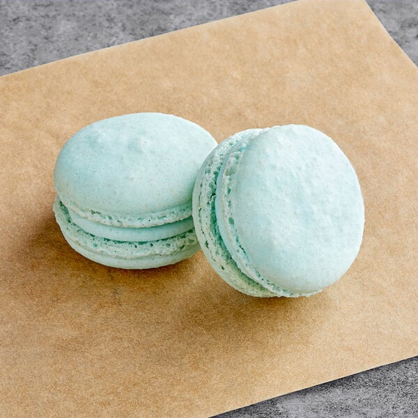 Two blue Macaron Centrale macarons on a brown surface.