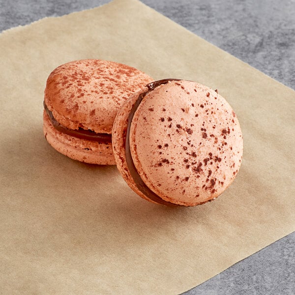 Two Nutella macarons on a piece of paper.