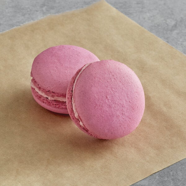 Two Macaron Centrale berry blend macarons on brown paper.