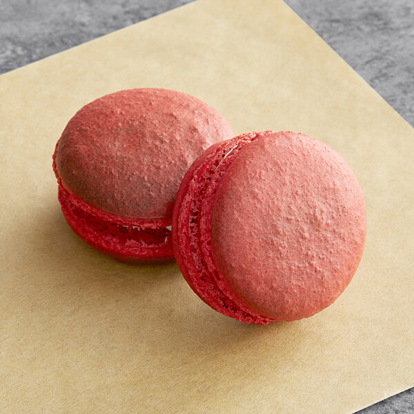 A pink and a red macaron on a table.