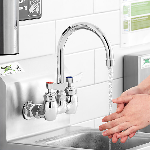 A person washing their hands under a Waterloo wall mount faucet with a gooseneck spout.