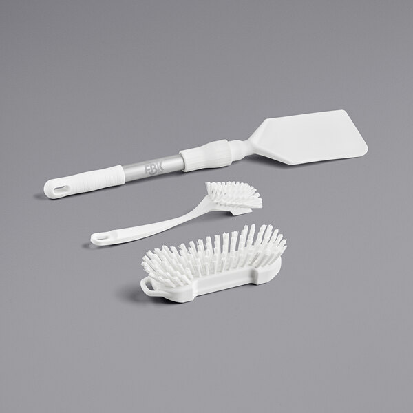 A white brush with a handle, comb, and toothbrush.