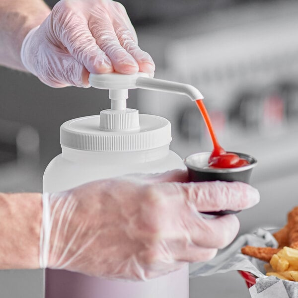 A person in gloves using a Choice condiment pump to pour ketchup into a container.