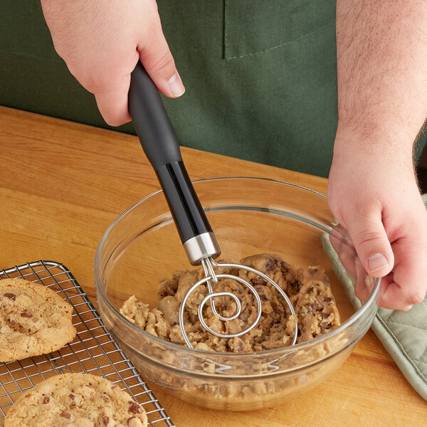 A hand using an OXO Good Grips dough whisk to mix cookie dough in a bowl.
