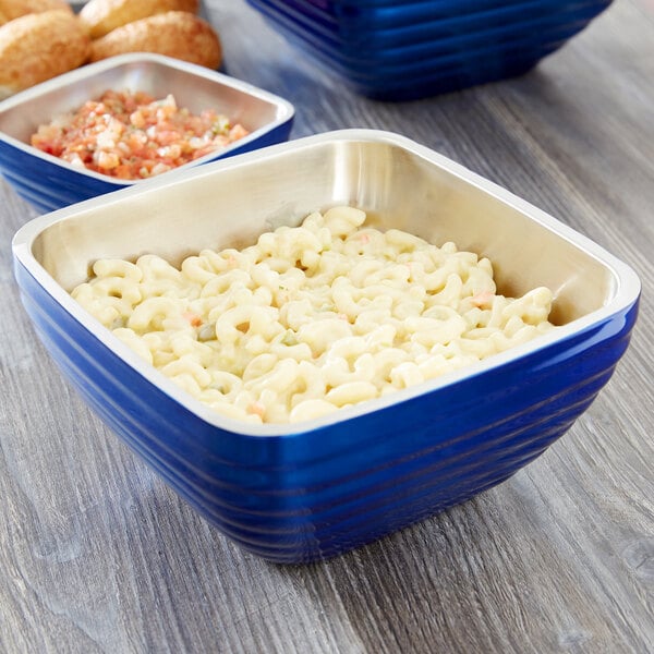A cobalt blue Vollrath double wall metal bowl filled with macaroni and cheese.